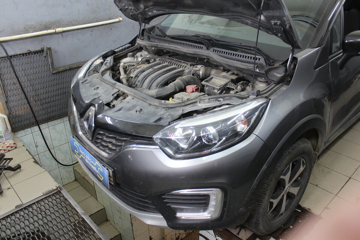 Dark grey vehicle with hood raised in garage workshop environment