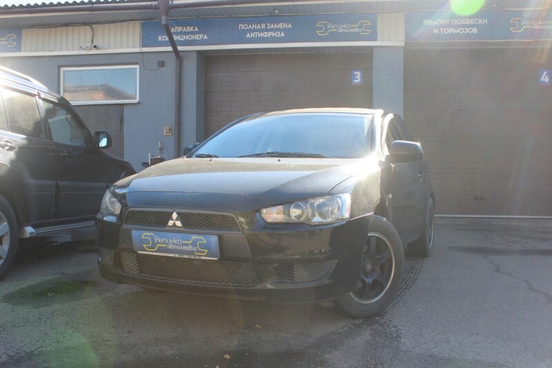 Тёмный седан Mitsubishi Lancer X на площадке автосервиса
