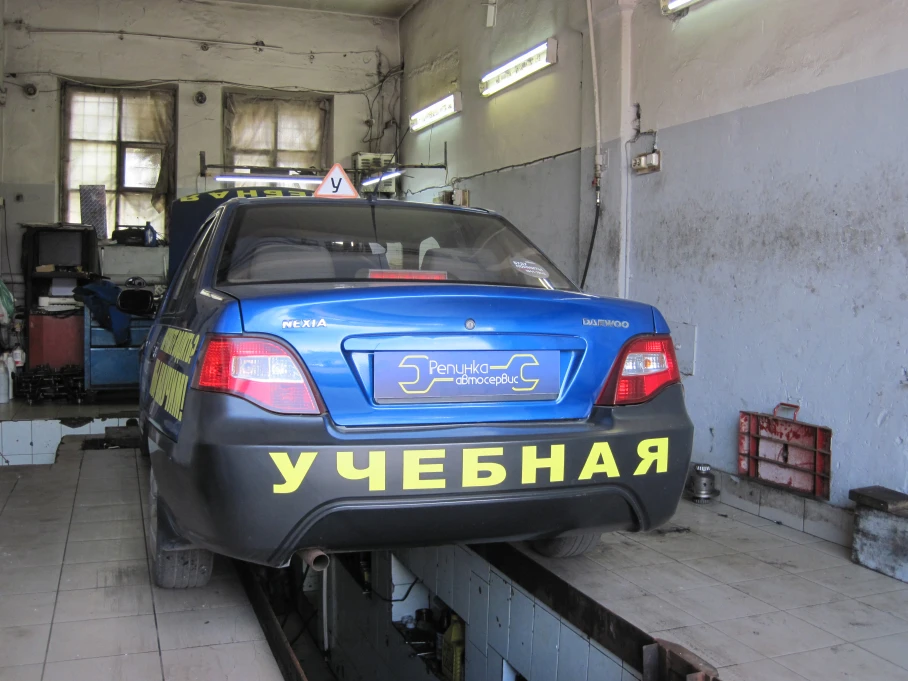 Мастер осматривает автомобиль на подъёмнике в автосервисе